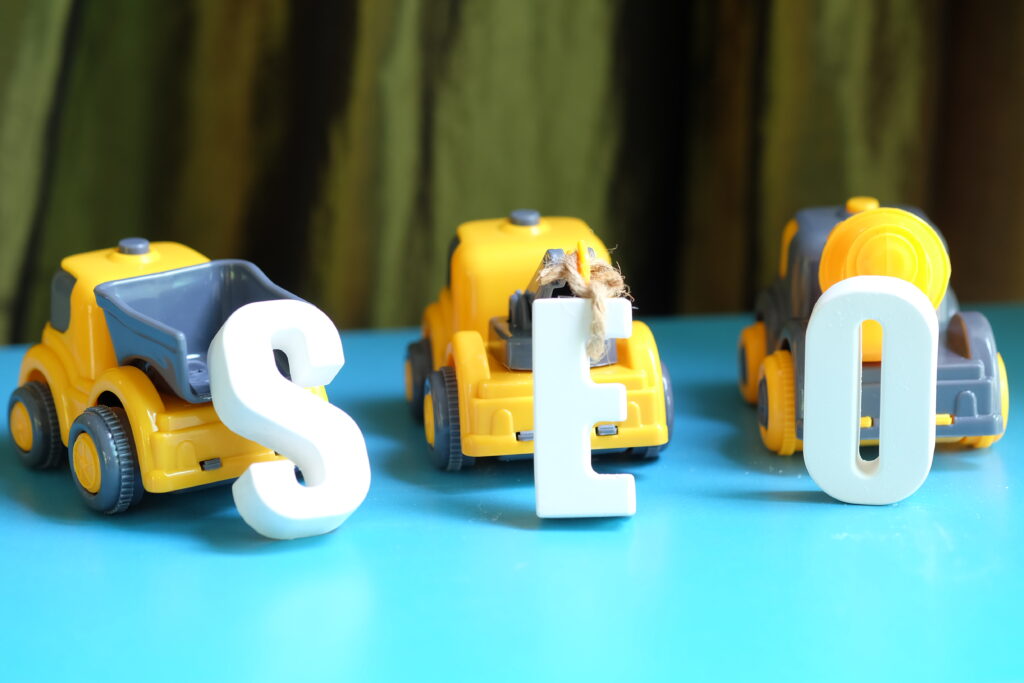 Photo of yellow toy trucks dragging the letters: S, E, and O
